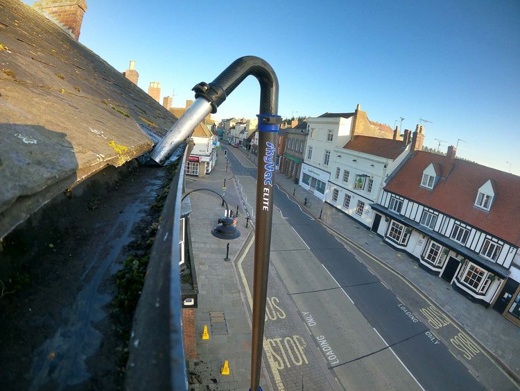 GoPro camera view from SkyVac vacuum pole at gutter height above commercial high street, showing extreme reach capability for tall commercial buildings