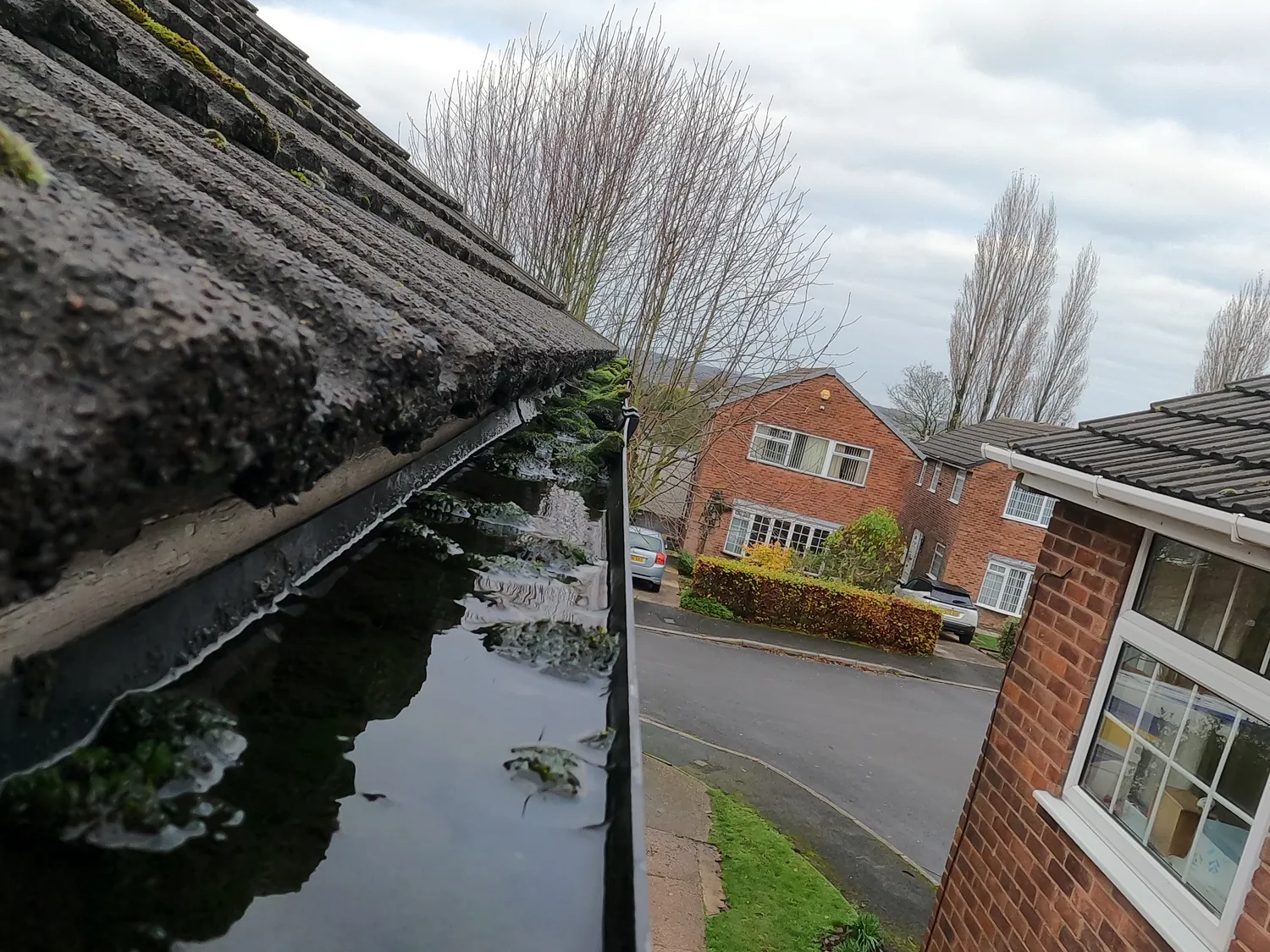 Blocked gutter holding water on Stiles Road, Arnold — moss from the tiles, before a SkyVac gutter clean