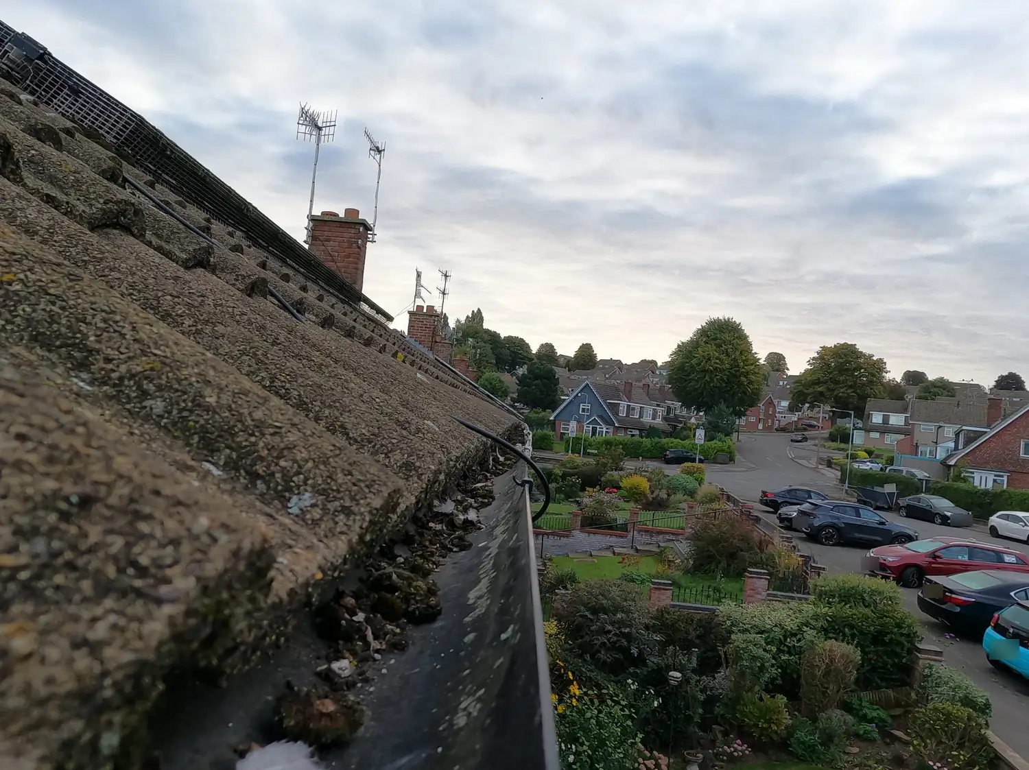 Blocked gutter full of moss on a 1960s house on Ramsey Drive, Woodthorpe, Nottingham NG5, with the estate and Woodthorpe Drive in the background, before a SkyVac clean